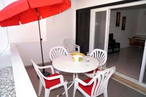 a white table and chairs with a red umbrella at 2 bedroom apartment in Vale do Lobo in Vale do Lobo