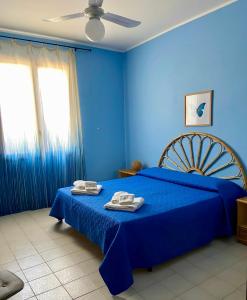 a blue bedroom with a blue bed with towels on it at Villa Vinci in Menfi