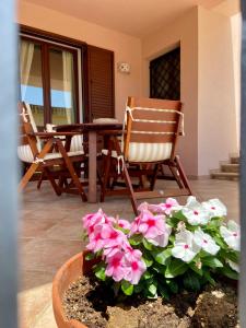 a patio with two chairs and a table and flowers at Villa Vinci in Menfi