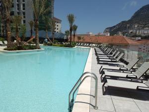 a swimming pool with lounge chairs in a hotel at BRAND NEW - Studio Apartments in EuroCity - Pool - Rock View - Balcony - Free Parking - Holiday and Short Let Apartments in Gibraltar in Gibraltar