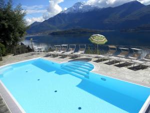 a large blue swimming pool with chairs and a mountain at Wonderful flat with swimming pool lift and garden in Gravedona