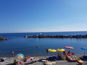 a group of people sitting on a beach with umbrellas at Appartamento silenzioso comodo alle spiagge e stazione ferroviaria in Lavagna