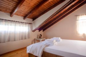 una camera da letto con un letto con lenzuola bianche e una finestra di Kohyli House ad Agia Pelagia Chlomou
