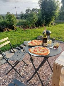 two pizzas sitting on a table with a bottle of wine at La Roulotte romantique des volcans in Saint-Saturnin