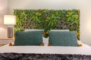 1 cama con 2 almohadas y pared verde en Le Tropical de Lamartine, en Limoges