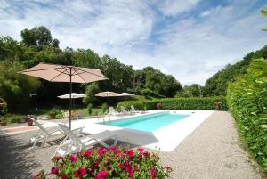 einen Pool mit Stühlen und einem Sonnenschirm in der Unterkunft Il Boschetto in Le Grazie