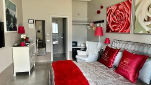 アンフォにあるB＆B レ ペロネのベッドルーム1室(赤い枕と椅子付きのベッド1台付)