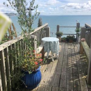 a wooden deck with a table and some plants and the ocean at Lyme Clifftop Hideaway in Lyme Regis