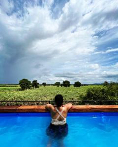 un hombre sentado en una piscina mirando a un campo en Royal Tusker Hotel, en Udawalawe