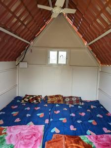 a bed in a room with a ceiling fan at Panshet Camping in Welhe +20 photos