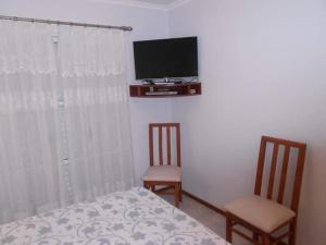 a bedroom with a bed and two chairs and a tv at Locaciones Colón in Colón