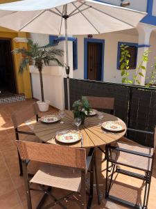a wooden table with plates of food and an umbrella at Casa Rodasa - 2 bedrooms, roof terrace, Airco, Front-terrace, Back-Patio, communal pool, etc in Roda