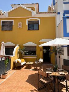 un patio con mesas y sombrillas frente a una casa en Casa Rodasa - 2 bedrooms, roof terrace, Airco, Front-terrace, Back-Patio, communal pool, etc, en Roda