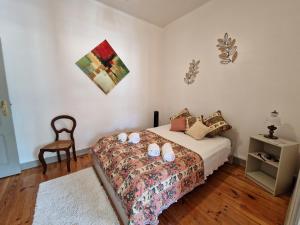 a bedroom with a bed with pillows and a chair at Casa Mosteiro in Alcobaça