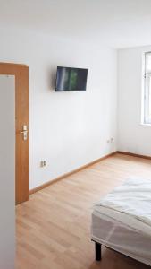 een witte kamer met een bed en een televisie aan de muur bij Chic Apartment with Parking place in Apolda