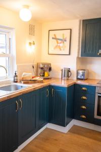 a kitchen with blue cabinets and a sink at Hall Cottage Bramfield Suffolk in Bramfield
