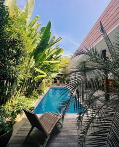 uma piscina com uma cadeira e uma palmeira ao lado de um edifício em Villa Panthera Bali em Uluwatu