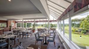 um restaurante com mesas e cadeiras e janelas grandes em Slieve Russell Hotel em Ballyconnell