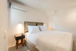 - une chambre blanche avec un lit et une table de nuit dans l'établissement Aura Villas Tinos, à Agios Romanos