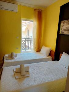two beds in a room with yellow walls and a window at Nefeli Maisonette in Nikiti