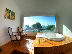 uma grande banheira num quarto com uma grande janela em Hotel Pé na Areia em Penha