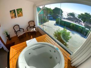 a bath tub in a room with a large window at Hotel Pé na Areia in Penha
