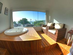 uma banheira num quarto com uma grande janela em Hotel Pé na Areia em Penha
