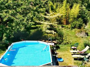 a swimming pool in a yard with chairs and trees at La Coticia en Pévèle in Coutiches