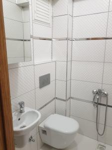a white bathroom with a toilet and a sink at Sıla Apart Otel in Bostancı