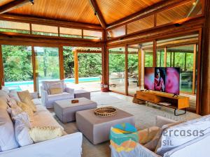 un soggiorno con mobili bianchi e TV a schermo piatto di Villa Ipanema, Praia do Forte a Praia do Forte