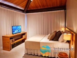 una camera da letto con un letto e una TV a schermo piatto di Villa Ipanema, Praia do Forte a Praia do Forte Altre 28 foto