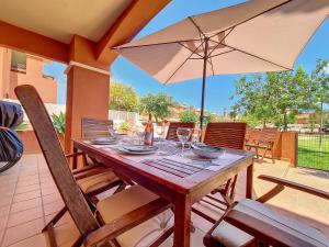 a wooden table with an umbrella on a patio at Albatros Playa 1 - 9609 in Mar de Cristal