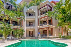 an apartment building with a swimming pool and palm trees at Macaw Oceans Club #2 in Jacó