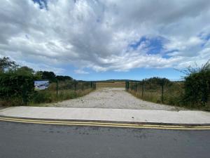 een lege weg met een hek aan de kant van de weg bij Thurstaston Field in Thurstaston