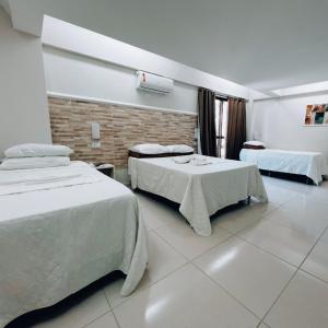 a hotel room with two beds and two tables at Pousada São Jorge in Porto De Galinhas