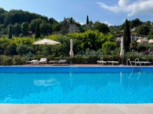 een zwembad met ligstoelen en een parasol bij Feli Holiday Home - Panoramic pool lake view in Gardone Riviera in Gardone Riviera