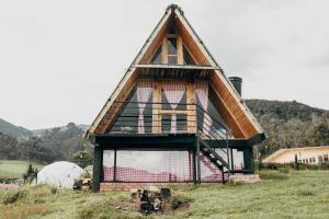 una pequeña casa con techo de paja en un campo en Glamping y cabañas en Neusa Cundinamarca, en La Esperanza