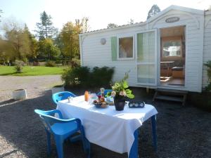 Camping des Bains في Saint-Honoré-les-Bains: طاولة مع قماش الطاولة البيضاء والكراسي الزرقاء