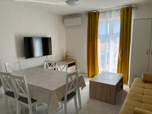 a living room with a table and chairs and a television at Apartments Zahtila - Berto in Rabac