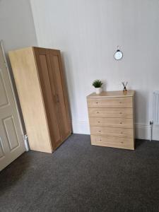 a room with a wooden cabinet and a dresser at Spacious Victorian Studio Flat in Doncaster