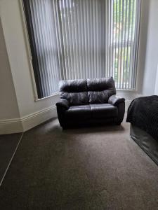 a leather couch sitting in a living room with a window at Spacious Victorian Studio Flat in Doncaster