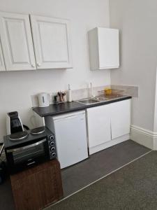 a kitchen with white cabinets and a sink and a microwave at Spacious Victorian Studio Flat in Doncaster