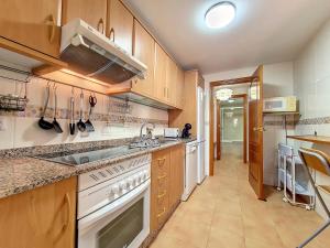 a kitchen with white appliances and wooden cabinets at Albatros Playa 1 - 9609 in Mar de Cristal