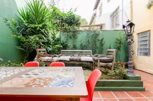 a patio with a table and chairs and a green wall at Quarto Zen in São Paulo