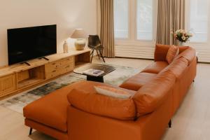 a living room with an orange couch and a flat screen tv at Blue Bird Residence Wijngaard in Antwerp