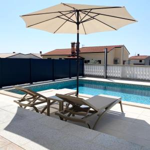 a pool with two lounge chairs and an umbrella at Apartment Komljenovic in Pula