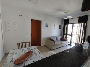 uma sala de estar com uma mesa e um sofá em Pérola Home - Guarujá no Guarujá