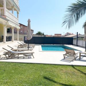 a swimming pool with lounge chairs and an umbrella at Apartment Komljenovic in Pula