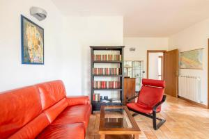 sala de estar con sofá de cuero y silla roja en Stanza con due letti singoli Le Vitterelle, en Zocca