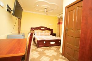 a bedroom with a bed and a table and a tv at Glory Hills Hotel in Kumasi